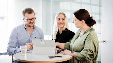 Besprechung Drei Mitarbeitende in einer Besprechung
