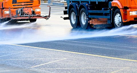Fahrzeuge sprühen Flüssigkeit auf die Straße Fahrzeuge sprühen Flüssigkeit auf die Straße