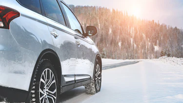 Mobilität im Winter Ein moderner SUV mit Allradantrieb steht am Straßenrand einer winterlichen Straße.