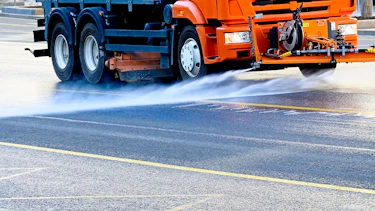 Fahrzeuge sprühen Flüssigkeit auf die Straße Fahrzeuge sprühen Flüssigkeit auf die Straße