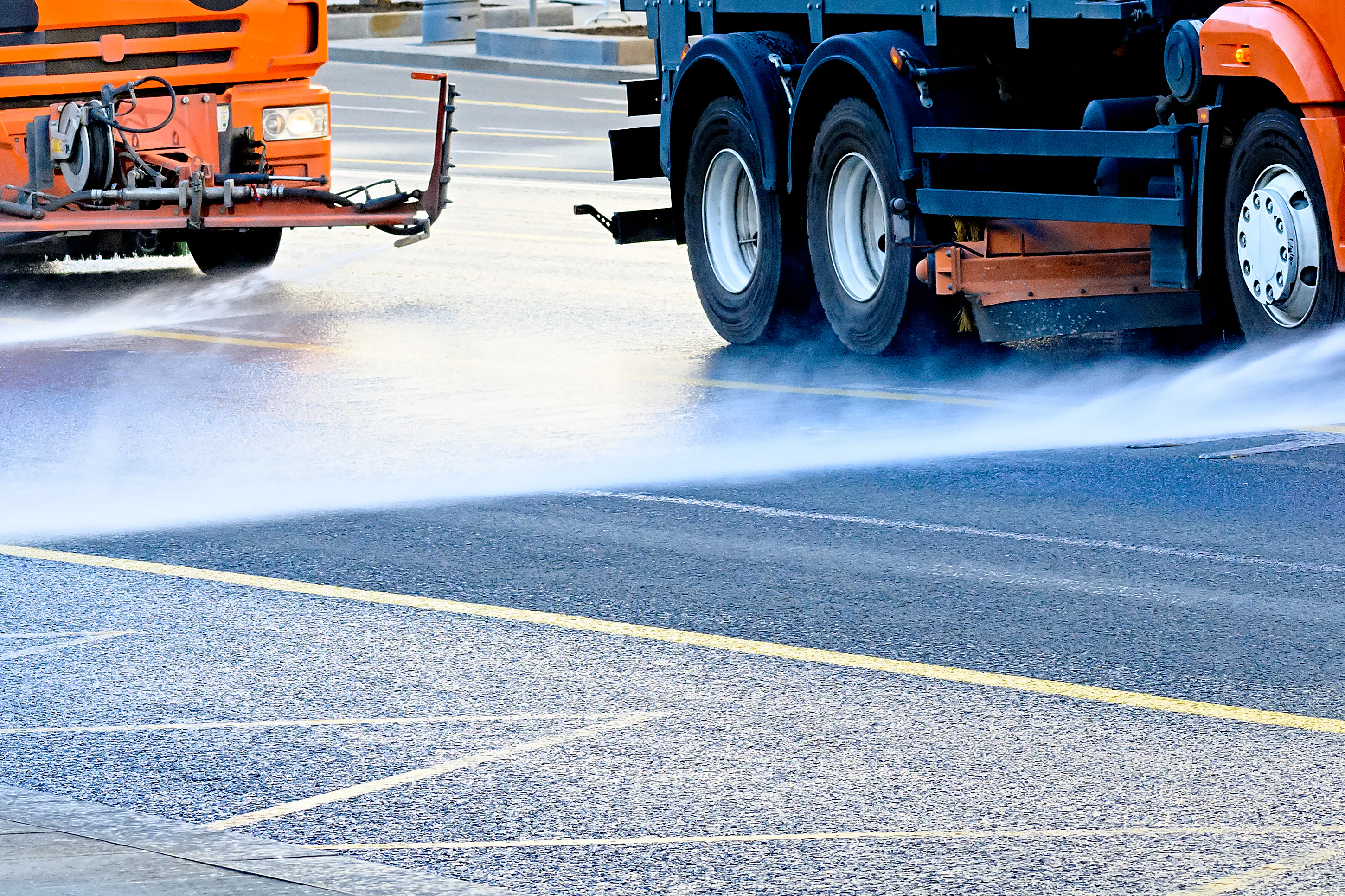 Fahrzeuge sprühen Flüssigkeit auf die Straße Fahrzeuge sprühen Flüssigkeit auf die Straße