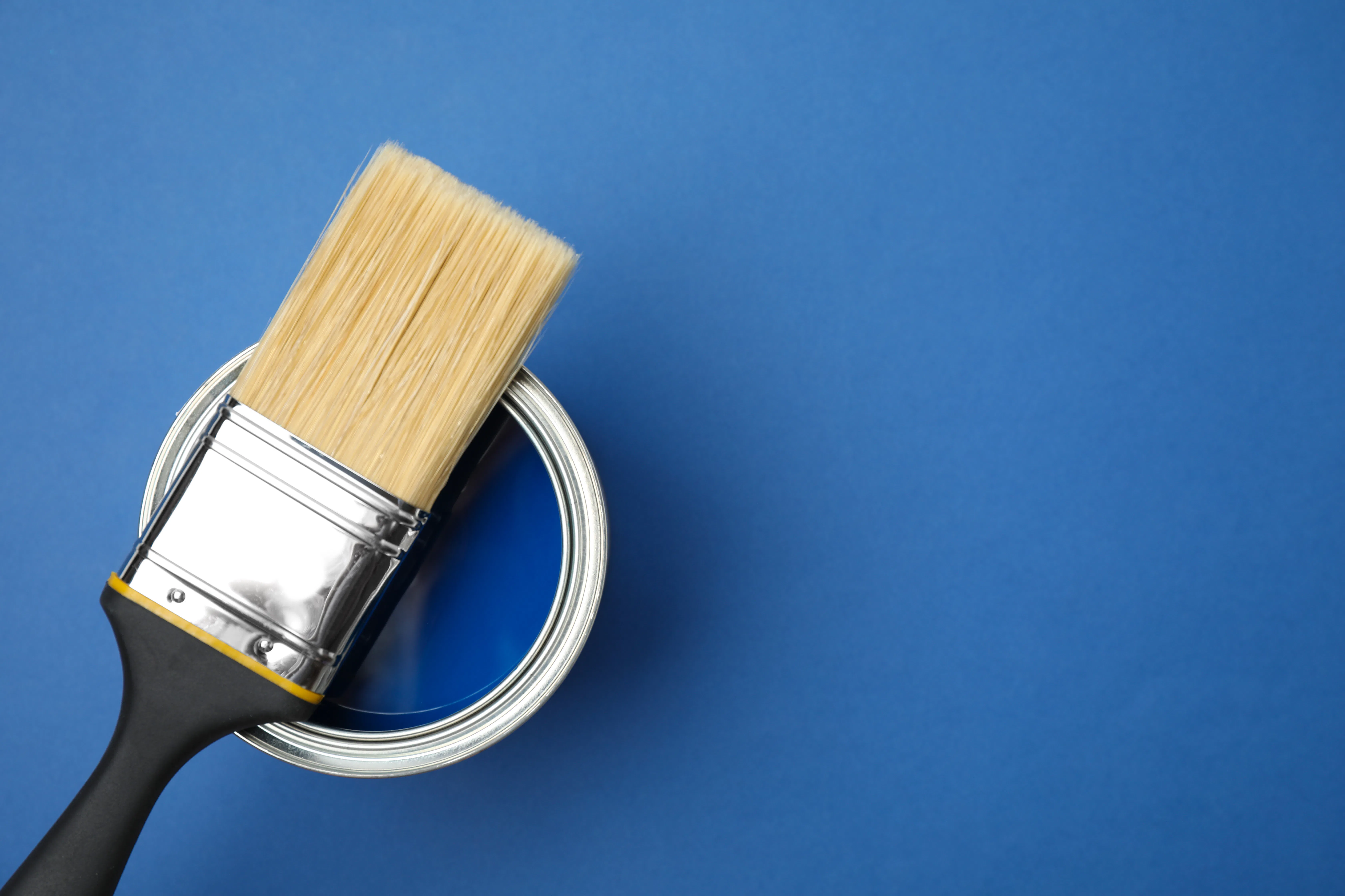 Open can and paint brush on blue background Open can and paint brush on blue background