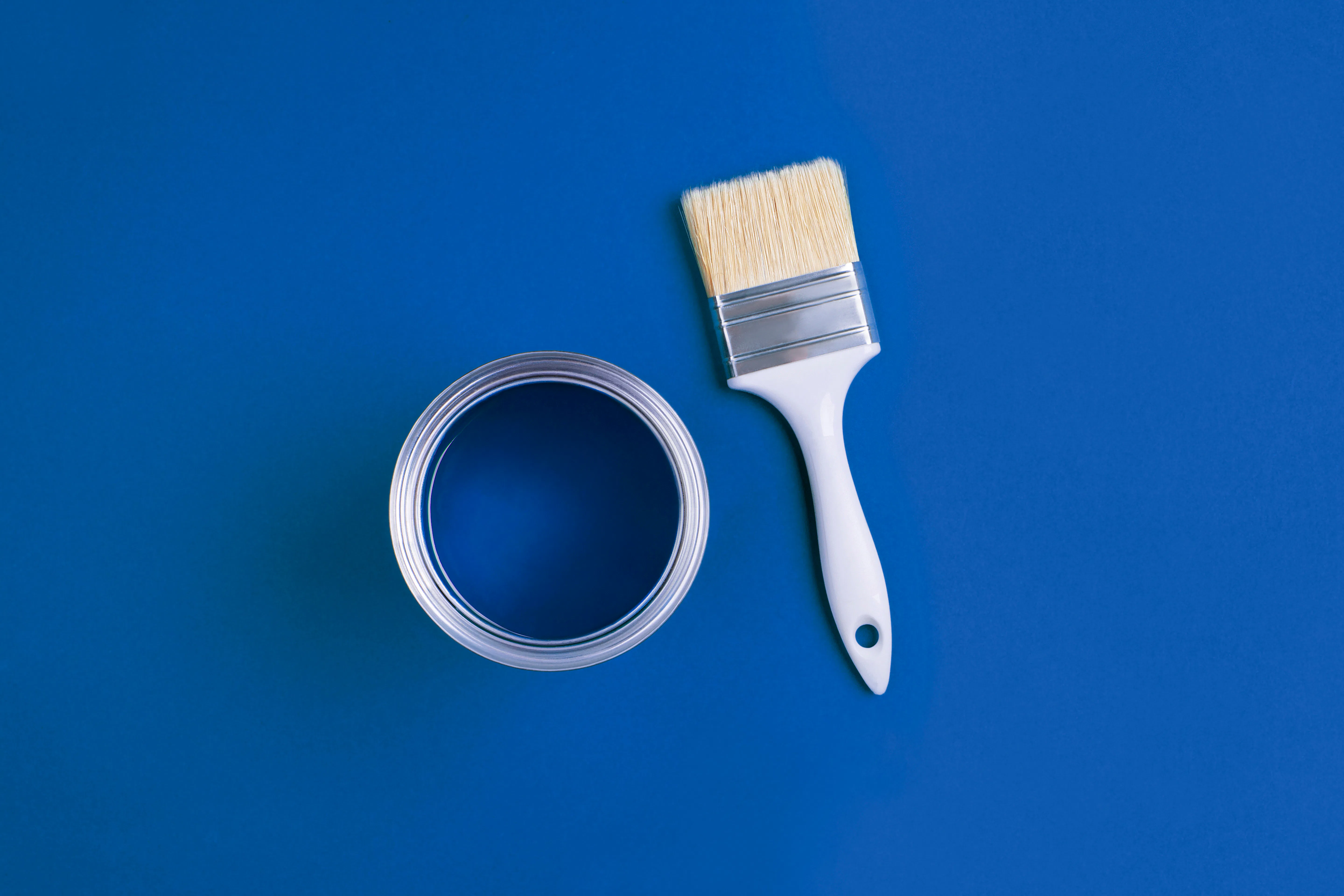 Open can and paint brush on blue background Open can and paint brush on blue background