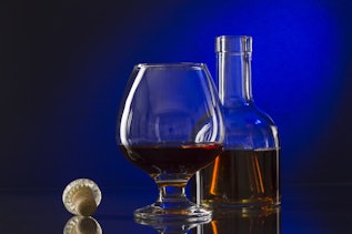 Cognac bottle and glass on blue blackground Cognac bottle and glass on blue blackground