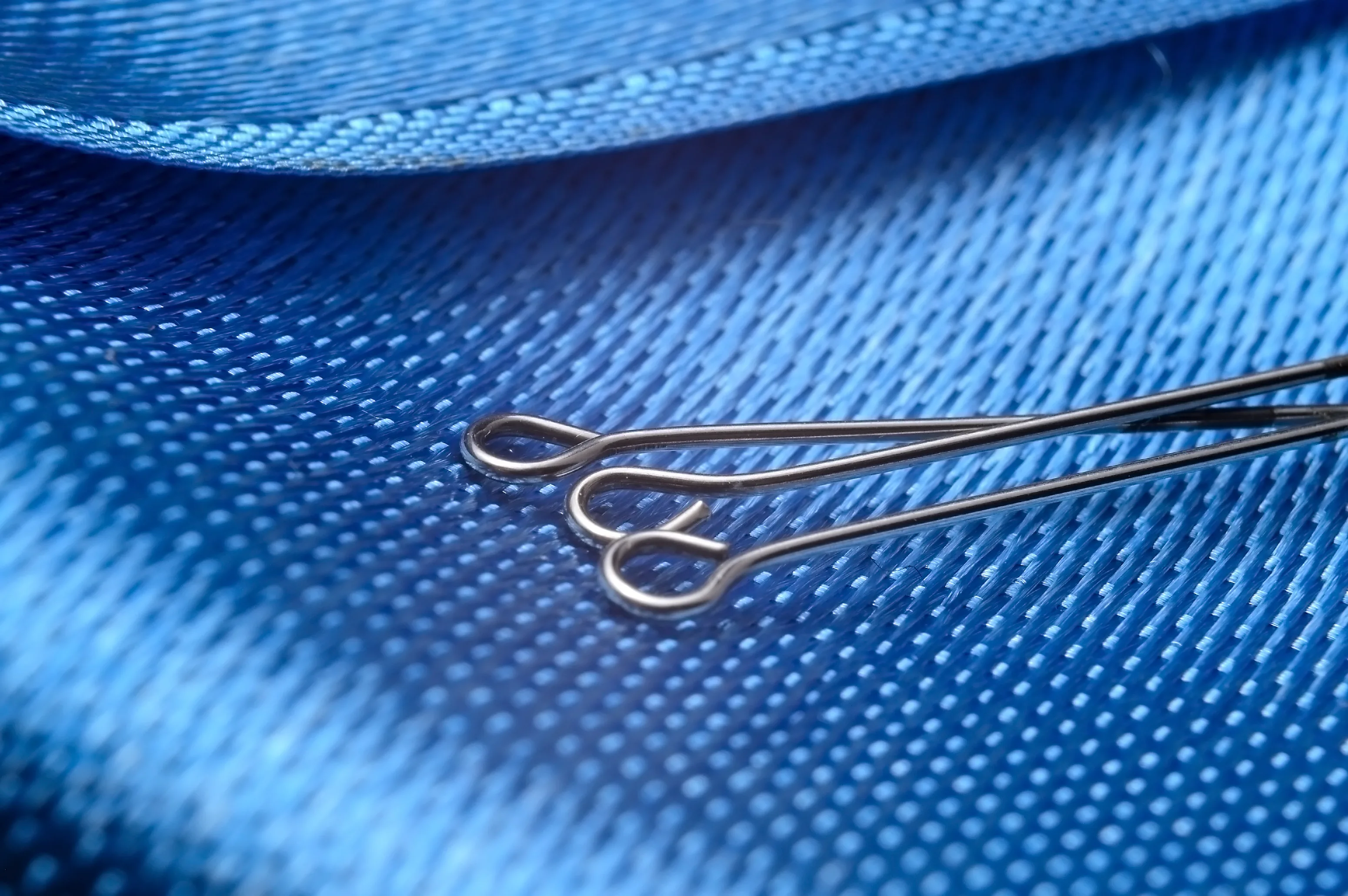 Three sewing pins on blue blackground Three sewing pins on blue blackground