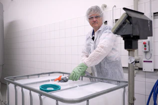 HACCP Bereich Ein Mitarbeiter füllt im HACCP Bereich am Standort Gablingen eine Chemikalie in Lebensmittelqualität in einen 1.000 Liter Kunststoff IBC