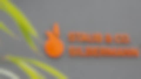 Firmenlogo STAUB & CO. - SILBERMANN GmbH Oranges Firmenlogo der STAUB & CO. - SILBERMANN GmbH an einer grauen Hauswand