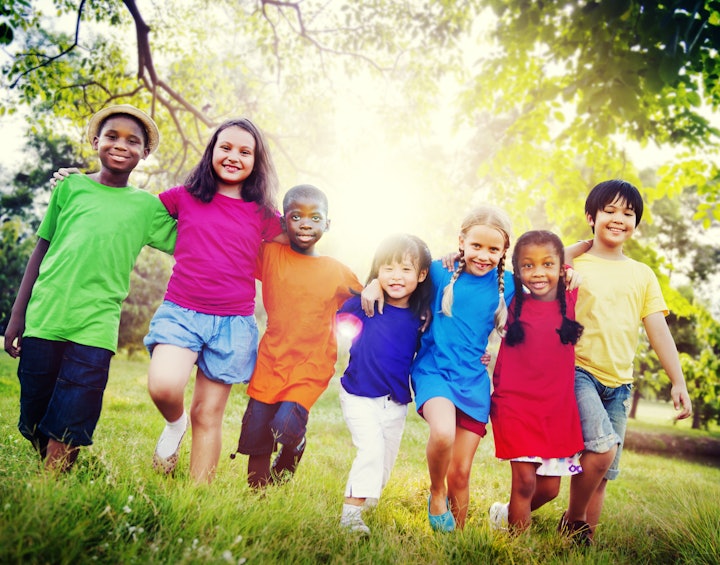 Laughing children in colorful clothes on a green meadow