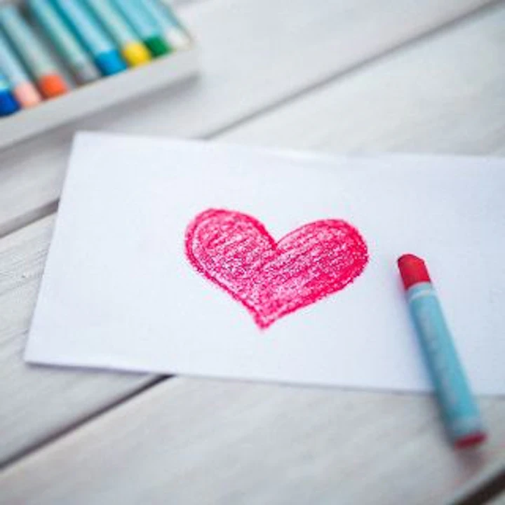 A pink heart painted with wax crayons on white paper.