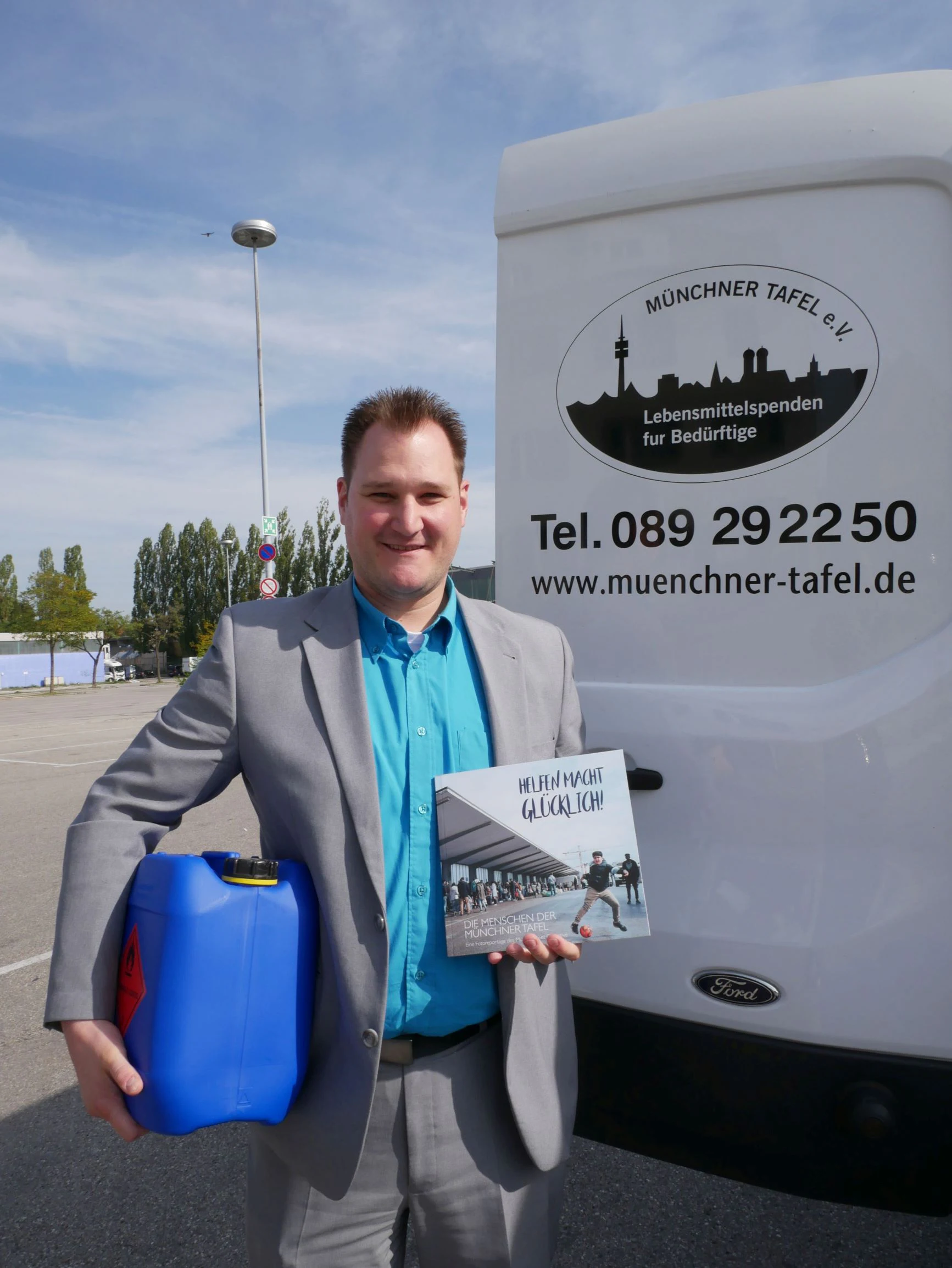 Albert Mai (Head of Sales at STAUB & CO. – SILBERMANN) Albert Mai (Head of Sales at STAUB & CO. – SILBERMANN), holding a canister of disinfectant and a brochure of Münchner Tafel e. V., in front of a Münchner Tafel e. V. delivery vehicle.
