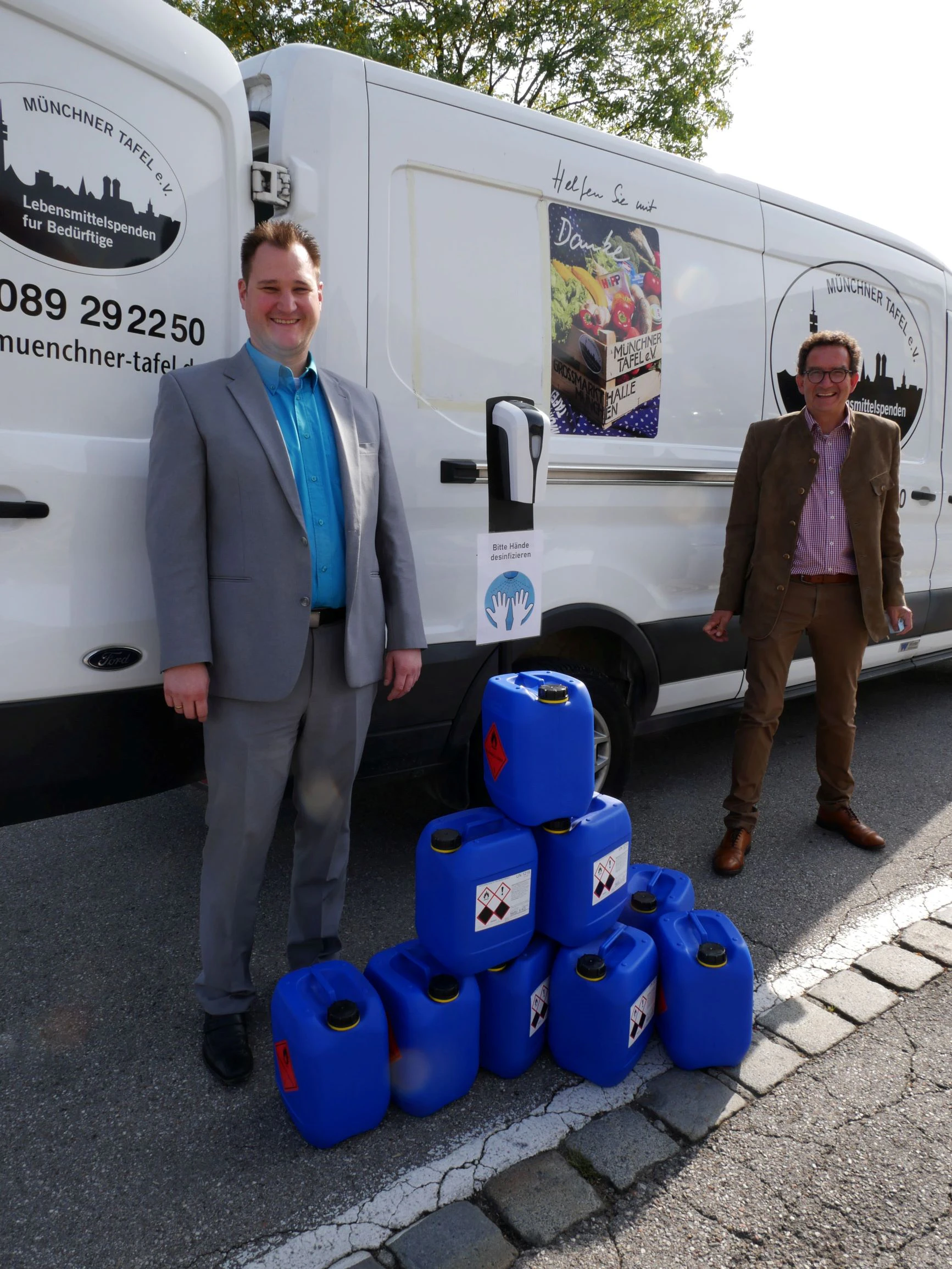 Albert Mai (Head of Sales at STAUB & CO. – SILBERMANN) and Matthias von Miller (Board Member of Münchner Tafel e. V.) at the presentation of the donated disinfectant to Münchner Tafel e. V. Albert Mai (Head of Sales at STAUB & CO. – SILBERMANN) and Matthias von Miller (Board Member of Münchner Tafel e. V.) with some canisters of disinfectant in front of a Münchner Tafel e. V. delivery vehicle.