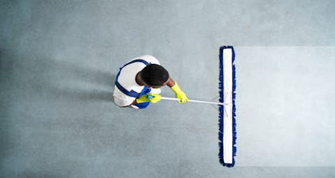 Male cleaner wipes the floor with a wide mop Male cleaner wipes the floor with a wide mop