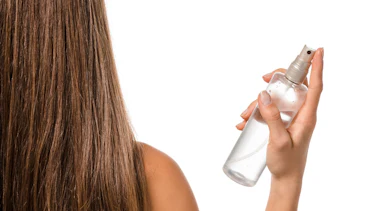 Person mit langen Haaren und Sprühflasche in der Hand Person mit langen Haaren und Sprühflasche in der Hand