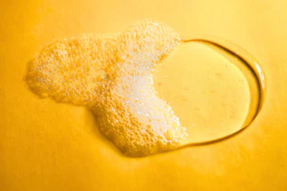 Liquid shower gel with foam on a yellow background Liquid shower gel with foam on a yellow background