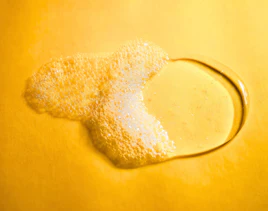 Flüssiges Duschgel mit Schaum auf gelber Oberfläche Flüssiges Duschgel mit Schaum auf gelber Oberfläche