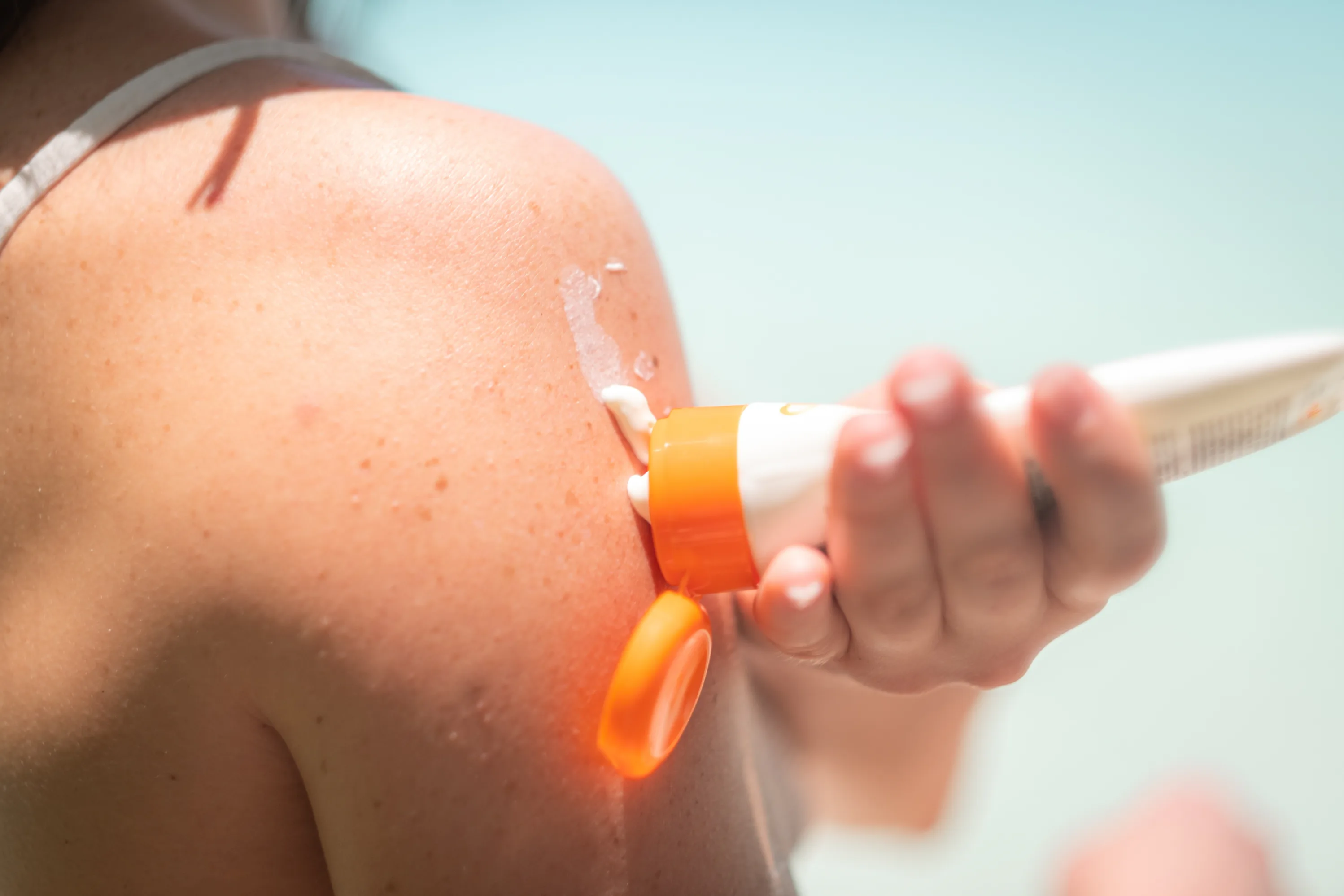 Sonnenschutz Eine Frau cremt sich im Freien den Arm mit Sonnencreme ein