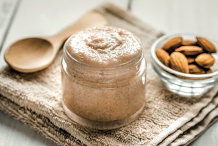 Cosmetic with scrub and almonds in background Cosmetic with scrub and almonds in background