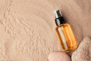 Brown cosmetic bottle with serum on sand background Brown cosmetic bottle with serum on sand background