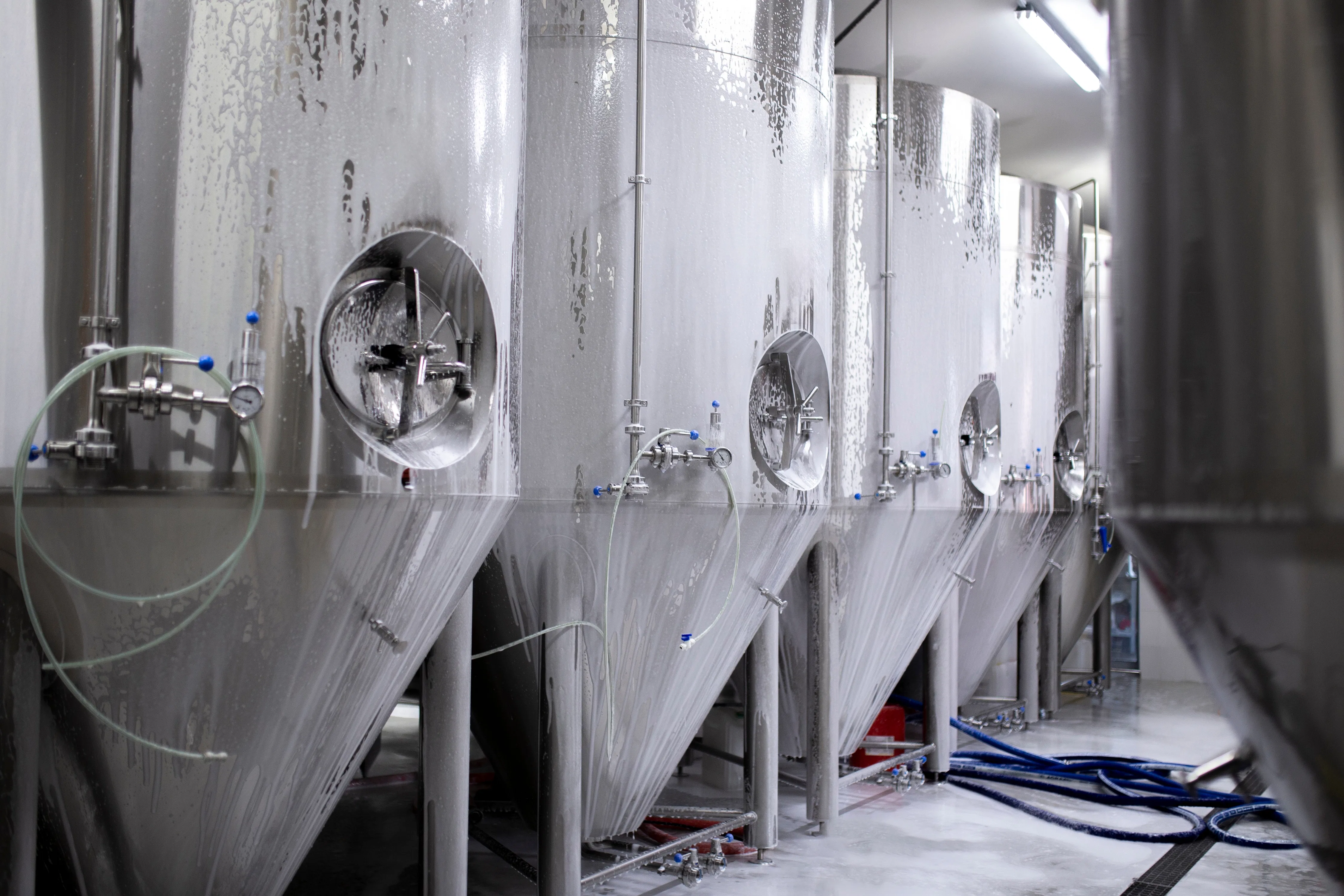 Reinigung großer Metalltanks im Lager einer Getränkefabrik Reinigung großer Metalltanks im Lager einer Getränkefabrik