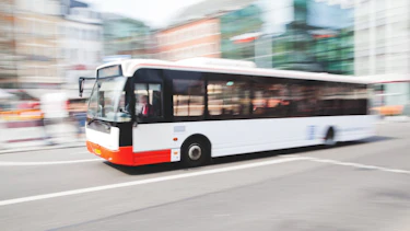 Stadtbus Ein Bus, der durch den Stadtverkehr fährt, mit Bewegungsunschärfe