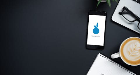 Cell phone with laptop on desk with coffee and a notepad