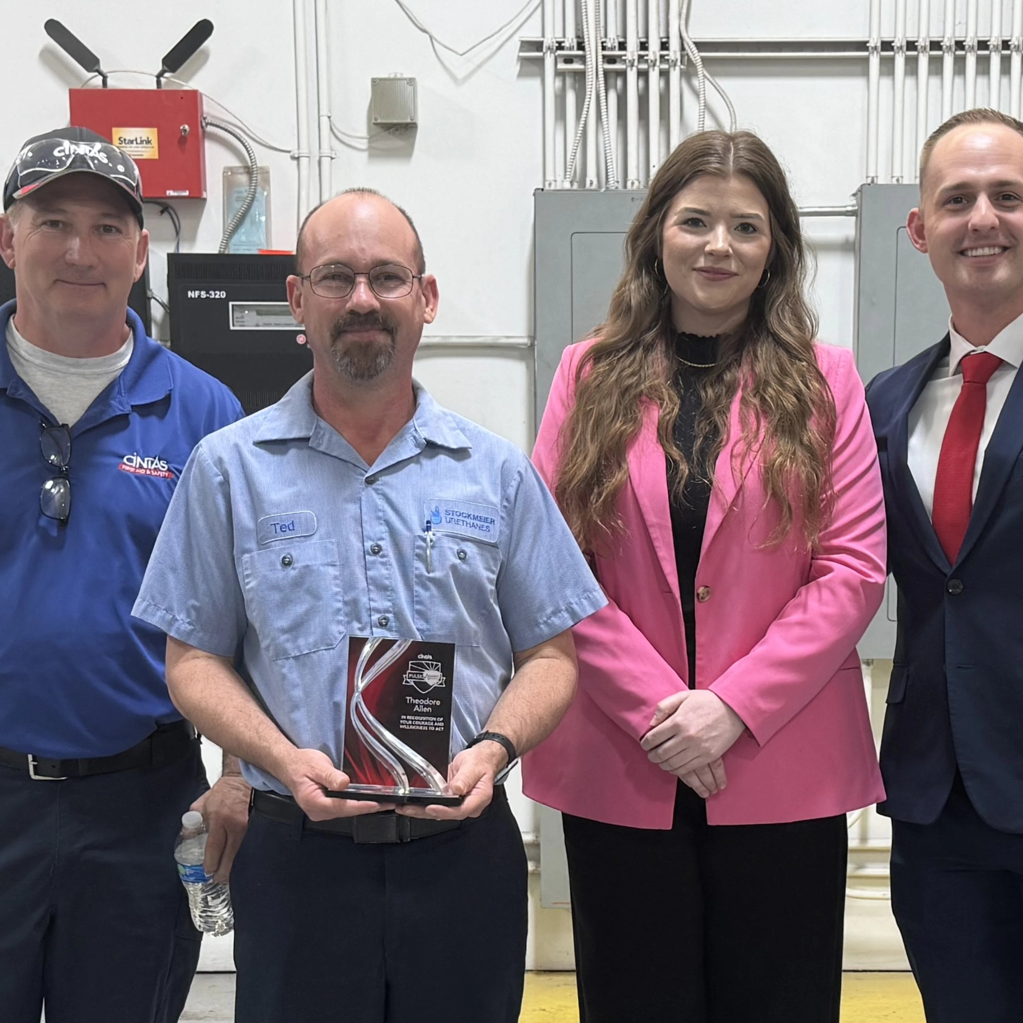 Employee Pulse Award recipient Ted Allen with Cintas representatives A group of four people standing in a facility setting at STOCKMEIER Urethanes USA, with one person holding a plaque award, celebrating employee recognition.