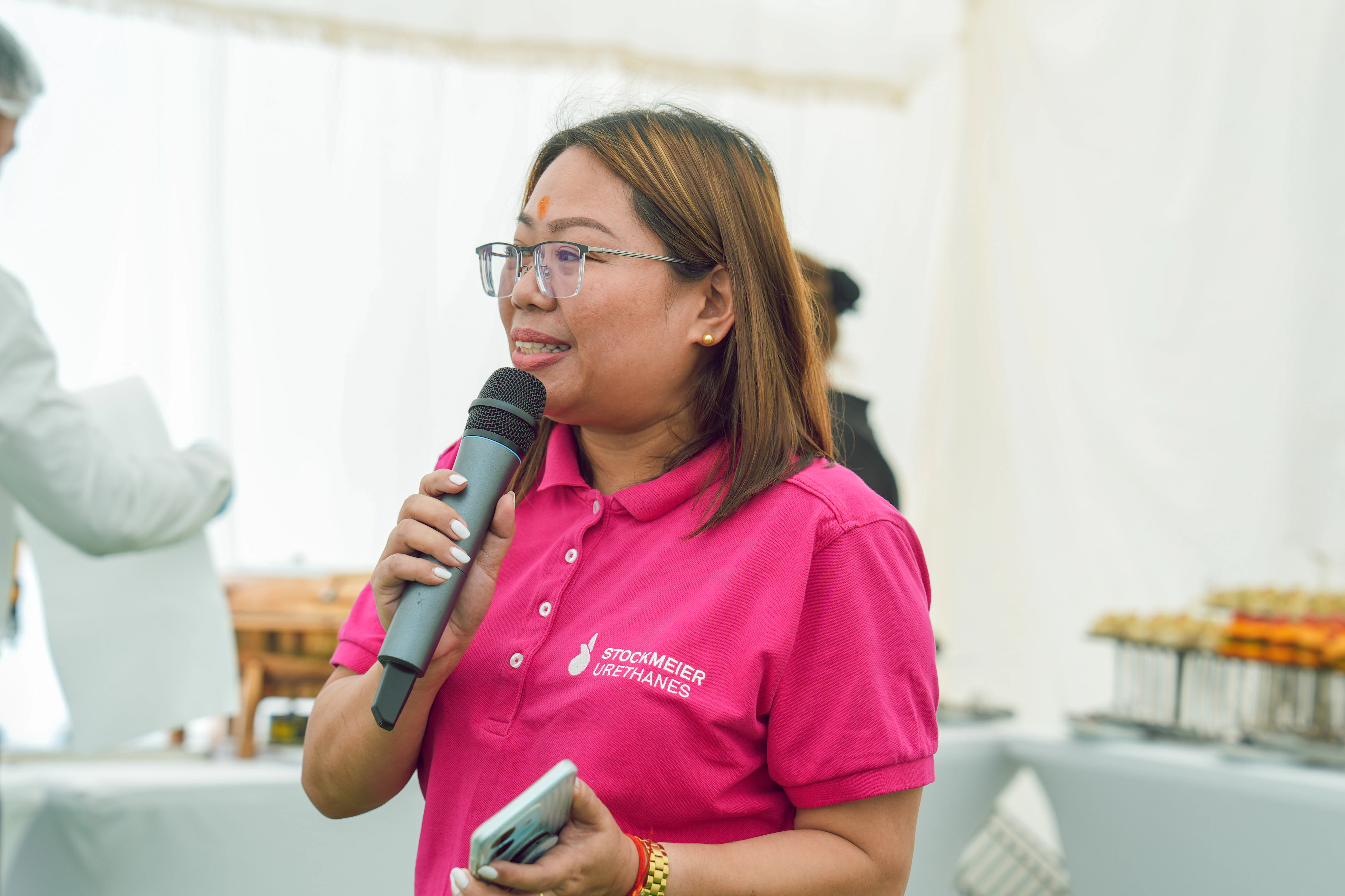 Cresilda Avenido hält eine Rede Die Mitarbeitende Cresilda Avenido spricht in ein Mikrofon