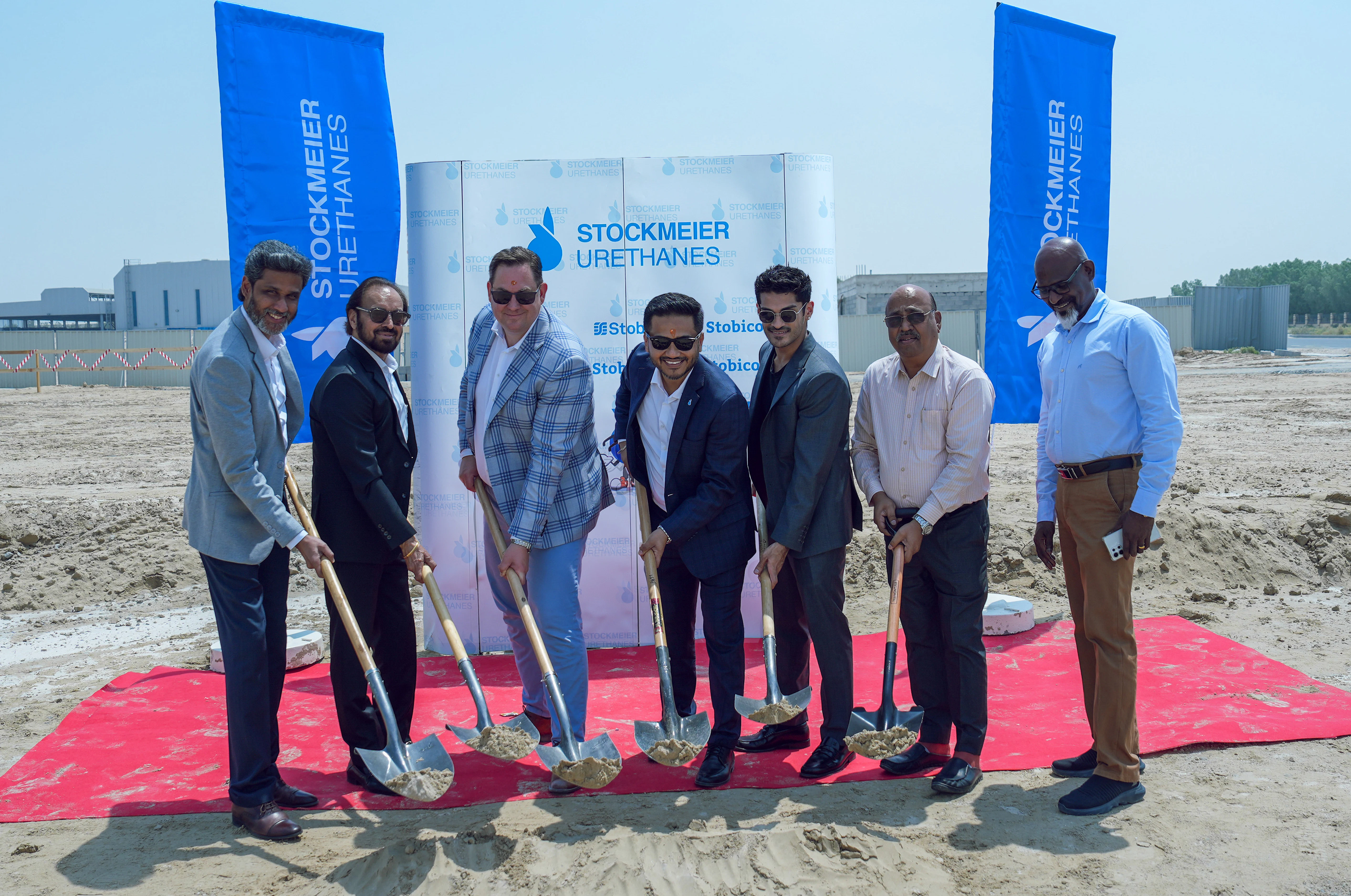 Das Dubai Team währen des Spatenstichs mit Partnern Sieben Männer mit Schaufeln in den Händen auf einem roten Teppich