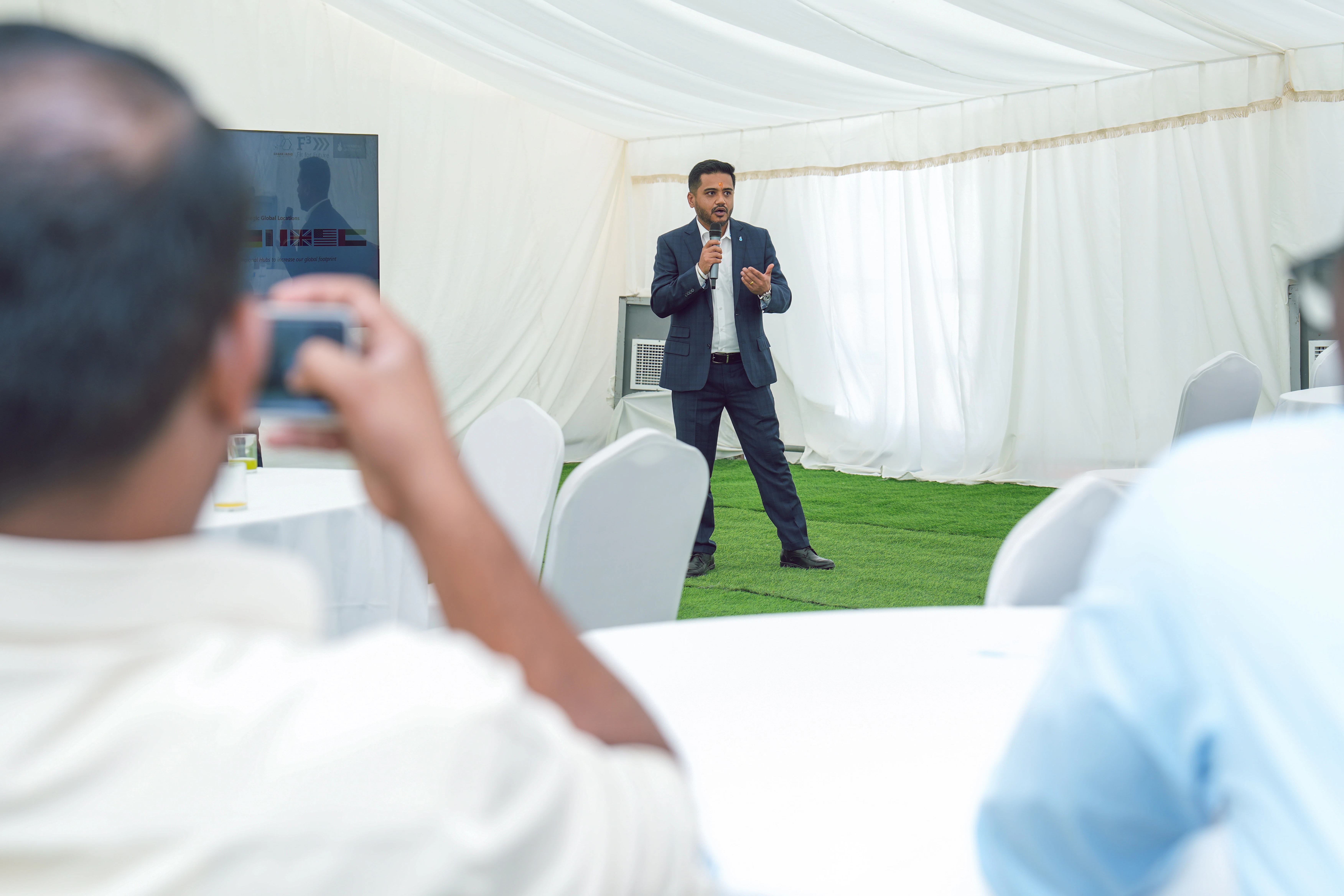 Ranjeet Singh hält eine Rede während des Events zum Spatenstich Man im Vordergrund macht ein Foto von Ranjeet Singh während er eine Rede hält