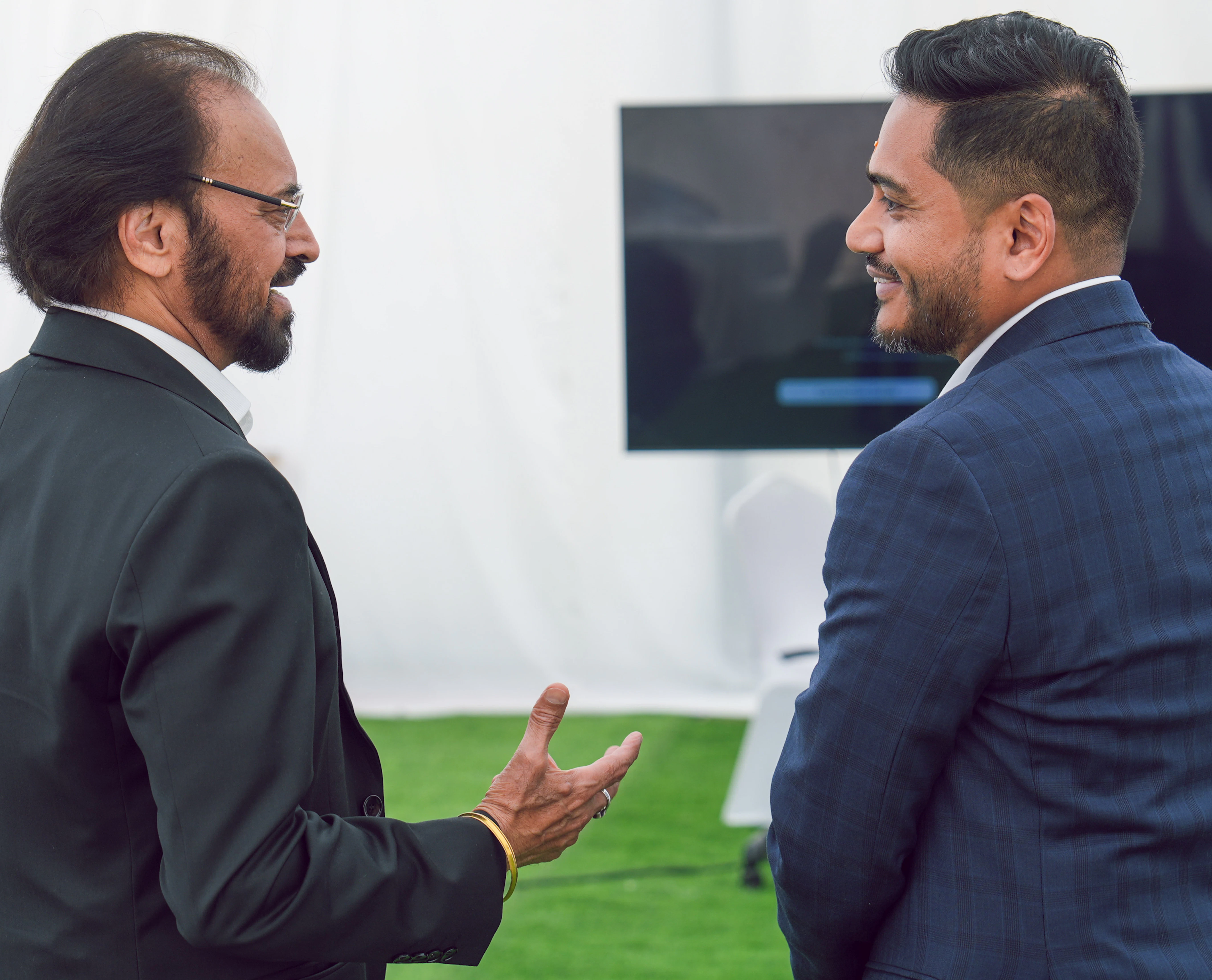 Ranjeet Singh spricht mit einem Gast Zwei Männer stehen mit dem Rücken zur Kamera während sie sprechen