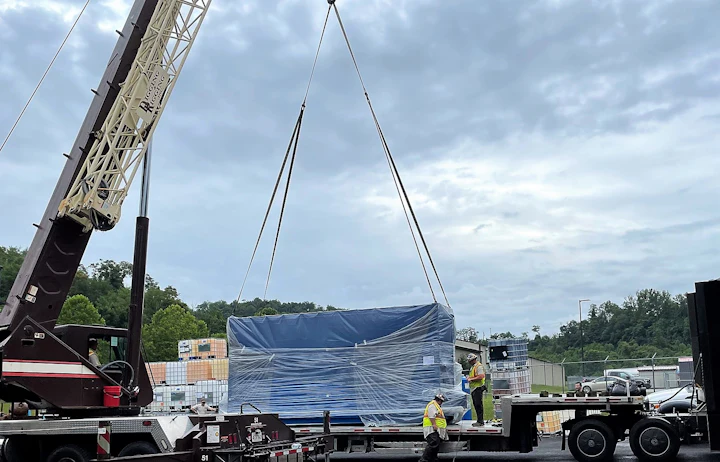 Kran an dem große blaue einfolierte Schränke hängen