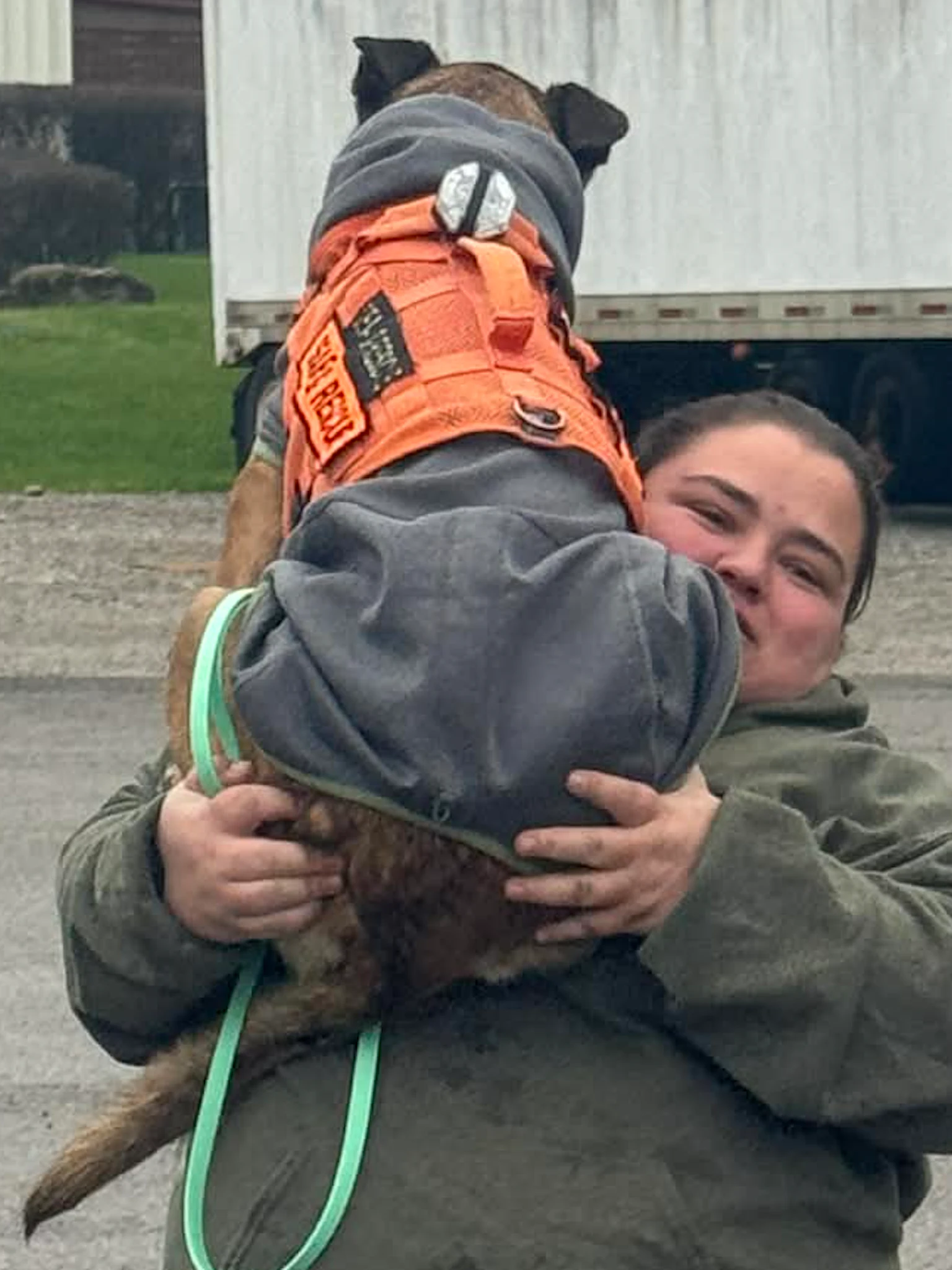 Kayla Tossone holding a K9 Kayla Tossone holding a K9 in her arms while standing in a parking lot