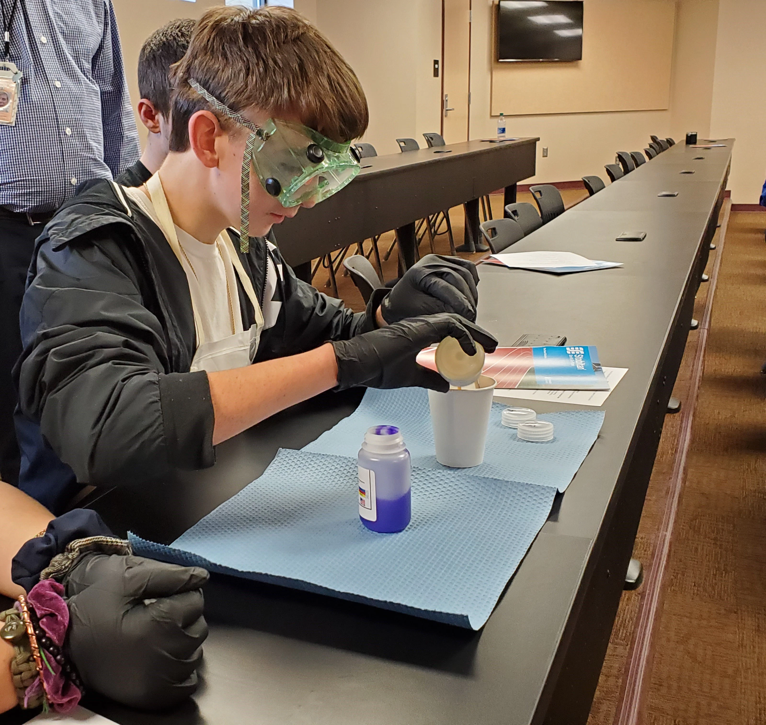 STOCKMEIER Urethanes kooperiert mit WVMA 10 Kind mit Schutzbrille und Handschuhen schüttet eine Flüssigkeit in einen Becher