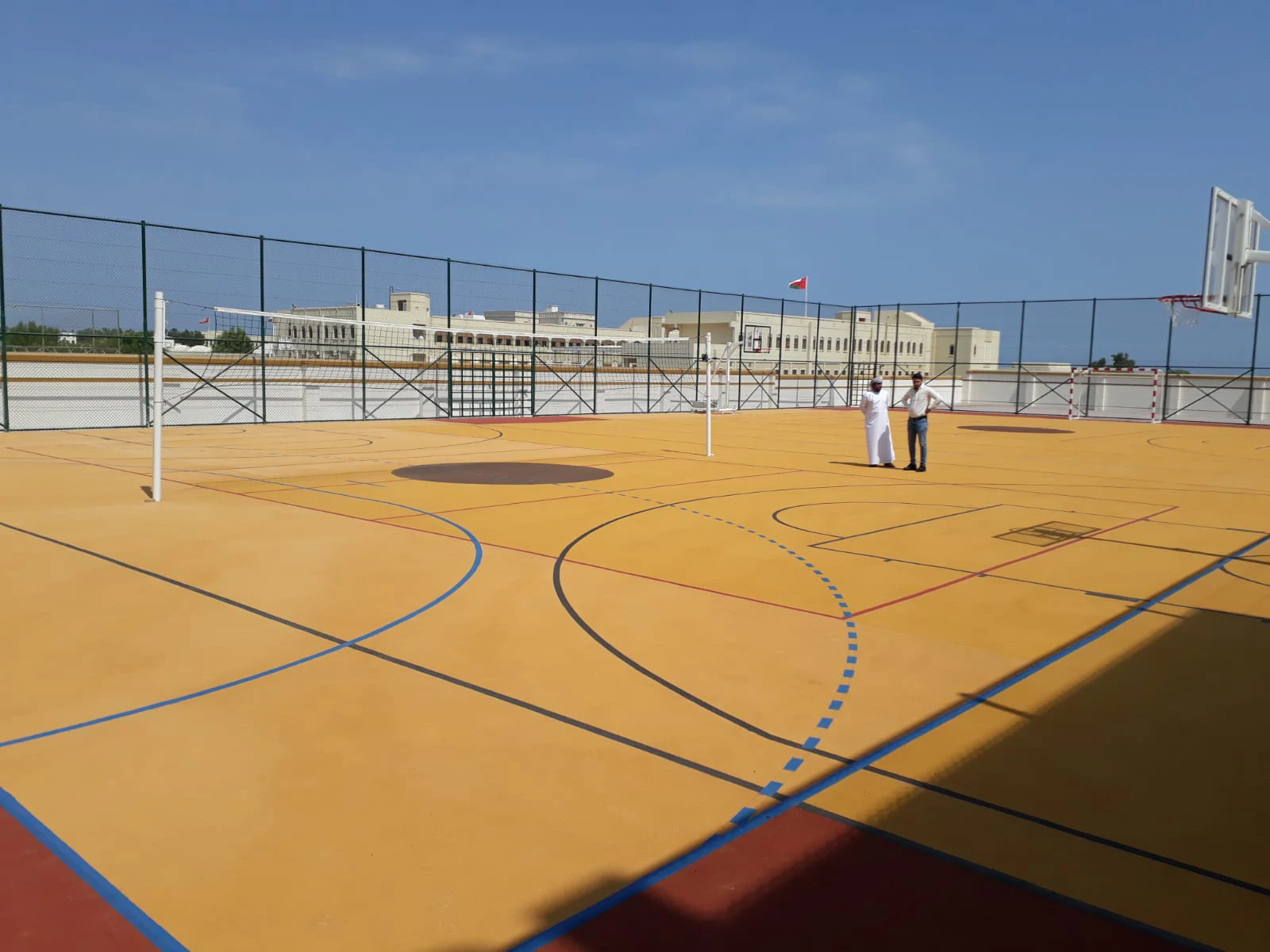 Freizeiteinrichtung für die königliche omanische Polizei in Oman 14 Zwei Männer stehen auf einem Sportplatz und schauen sich den Boden an